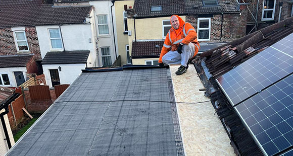 a man on a flat roof in the middle of installing a rubber flat roofing material onto a roof