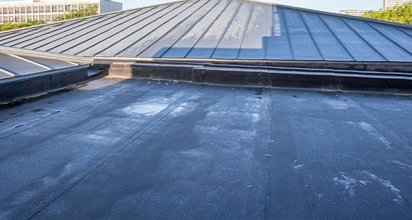 a felt flat roof with water on it in an urban environment