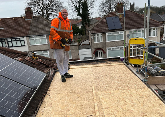 a person in the middle of installing the underlay on a flat roof in a suburban neighbourhood 